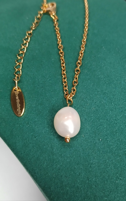 Gold chain necklace with a pearl pendant on a green background