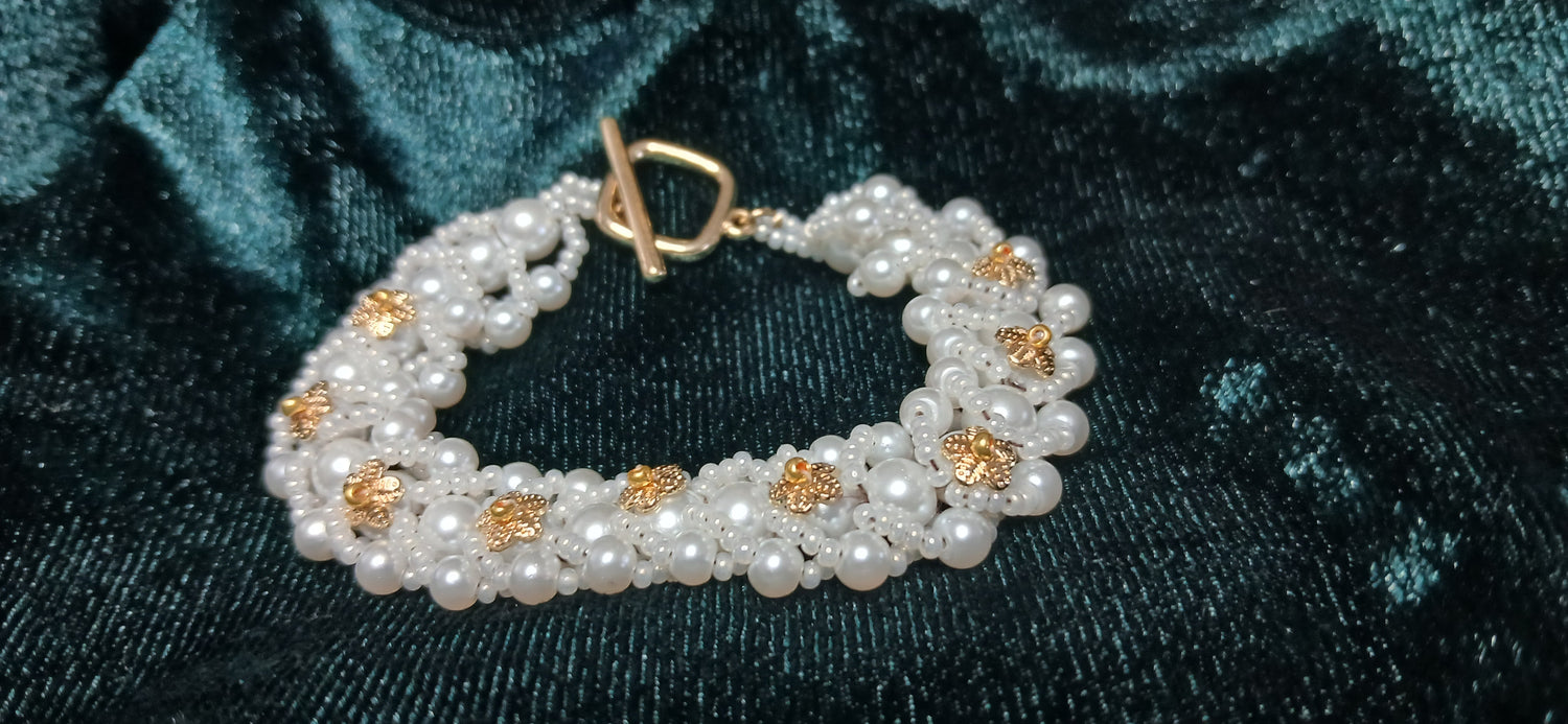 Pearl bracelet with gold accents on a dark green velvet background