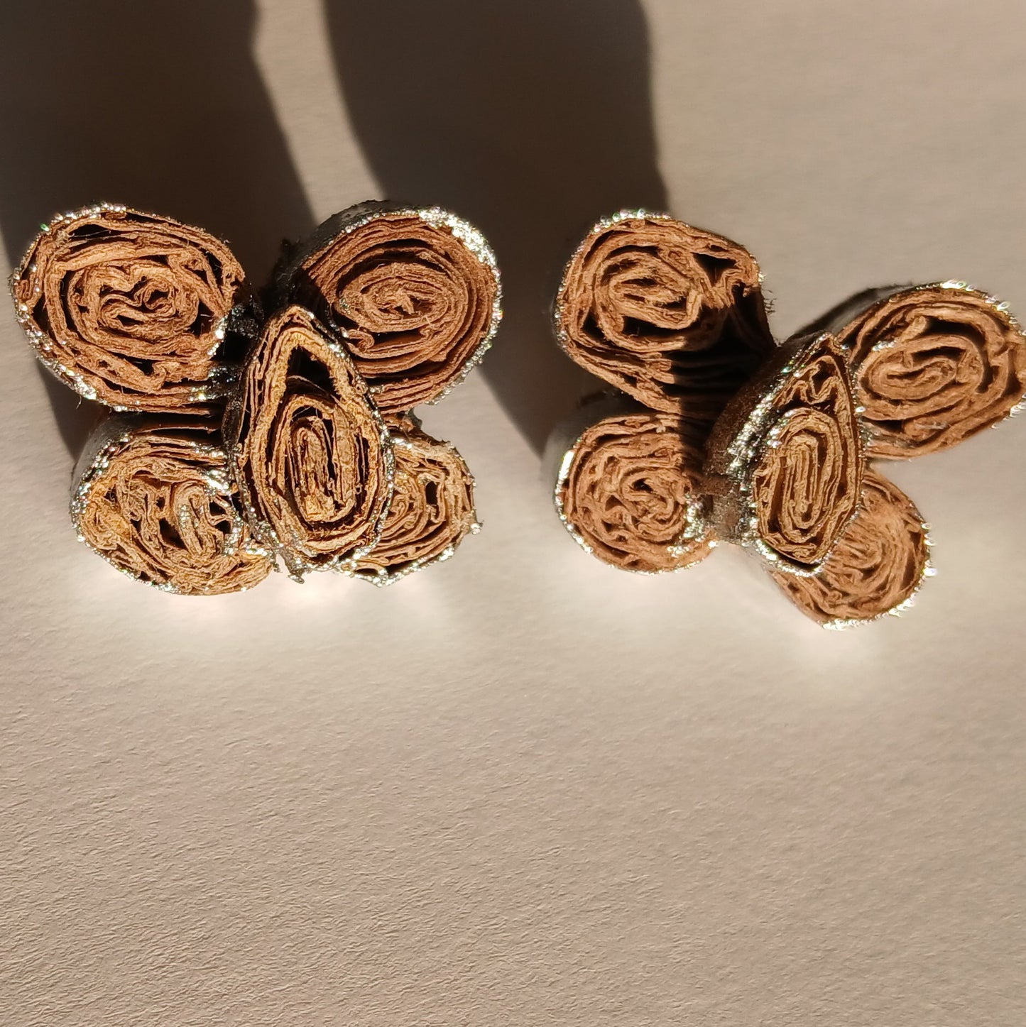 Pair of gold butterfly-shaped earrings on a beige background