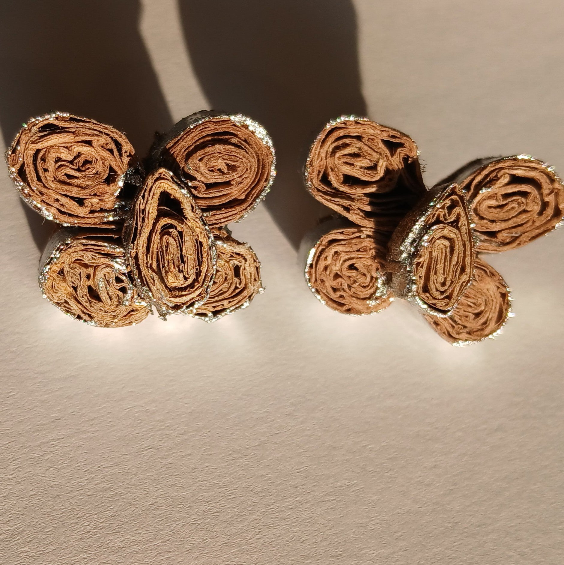 Pair of gold butterfly-shaped earrings on a beige background